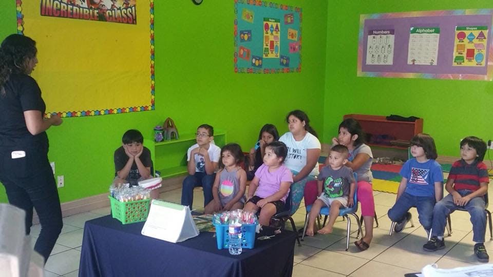 Person speaking to a group of children and adults in a classroom