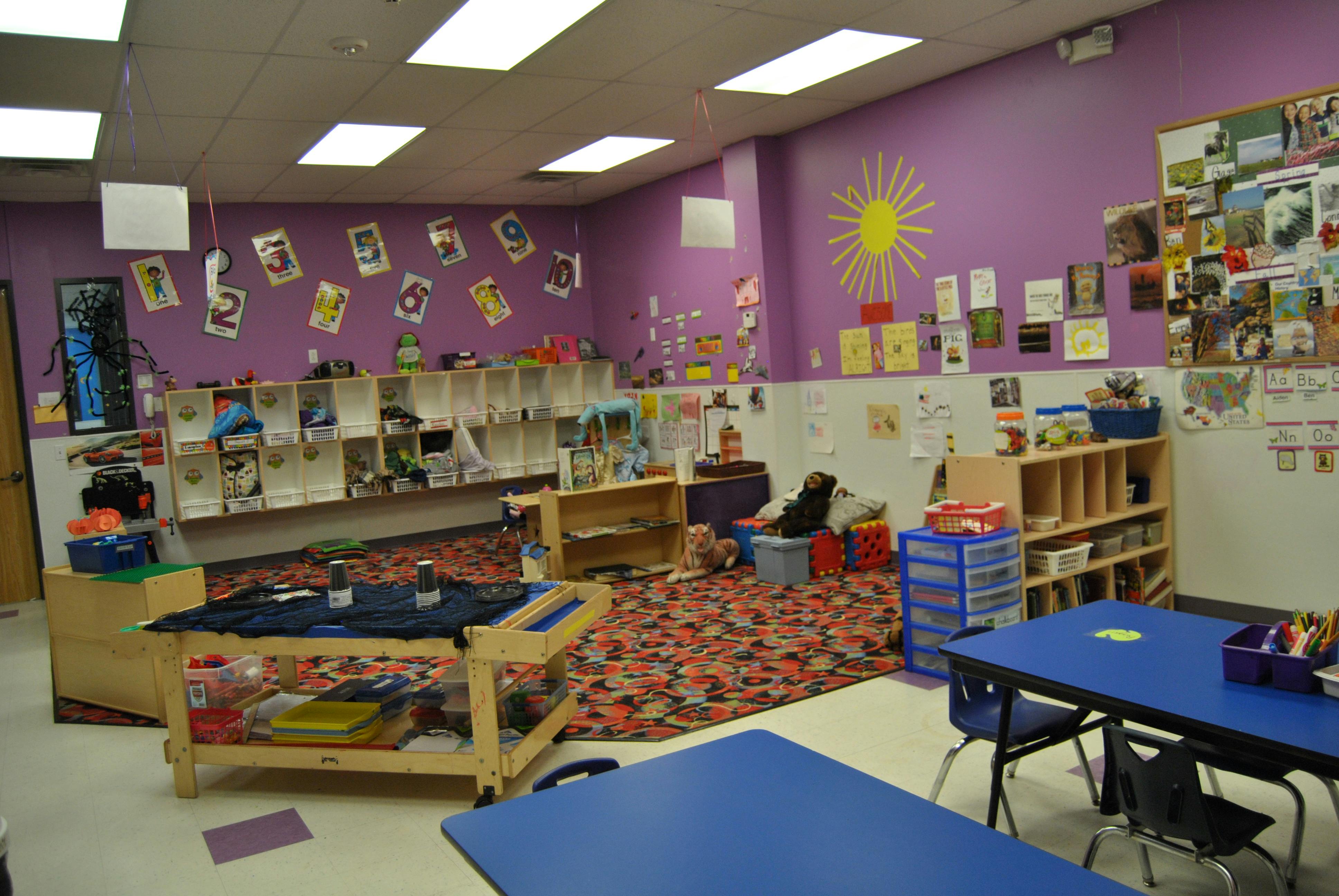 Classroom with purple walls, colorful rug, tables, and shelves