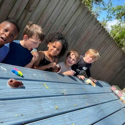 Five children eating cupcakes at a picnic table
