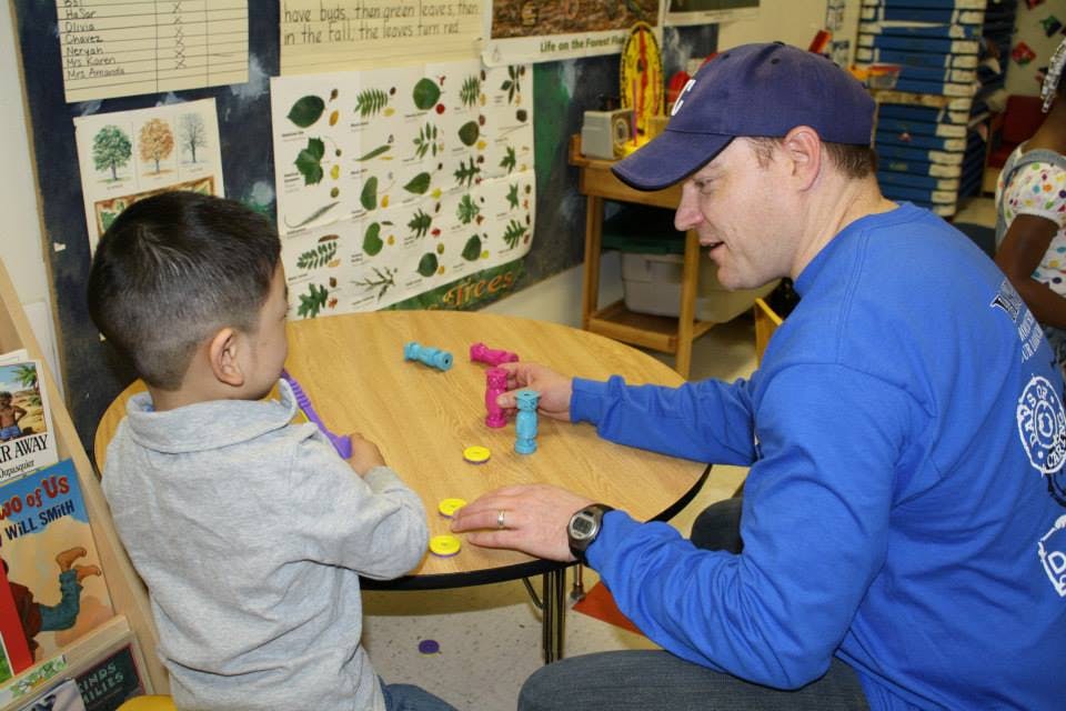 Adult and child playing with colorful blocks and tokens at a table