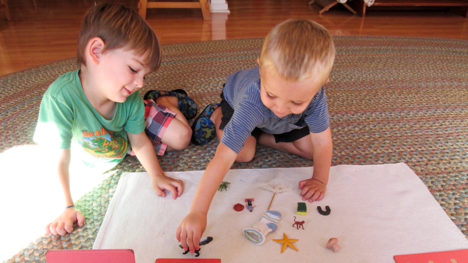 Two children playing with small objects on a white mat
