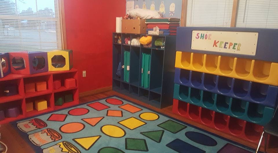Classroom with a colorful rug, shelves, and a shoe keeper
