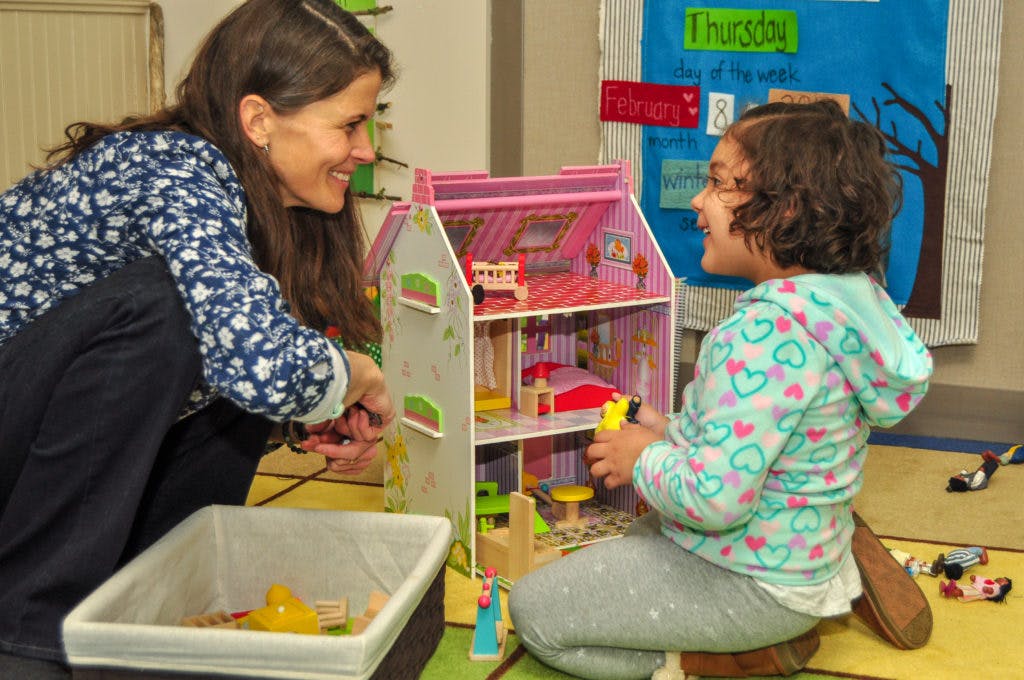 Person and child playing with a dollhouse
