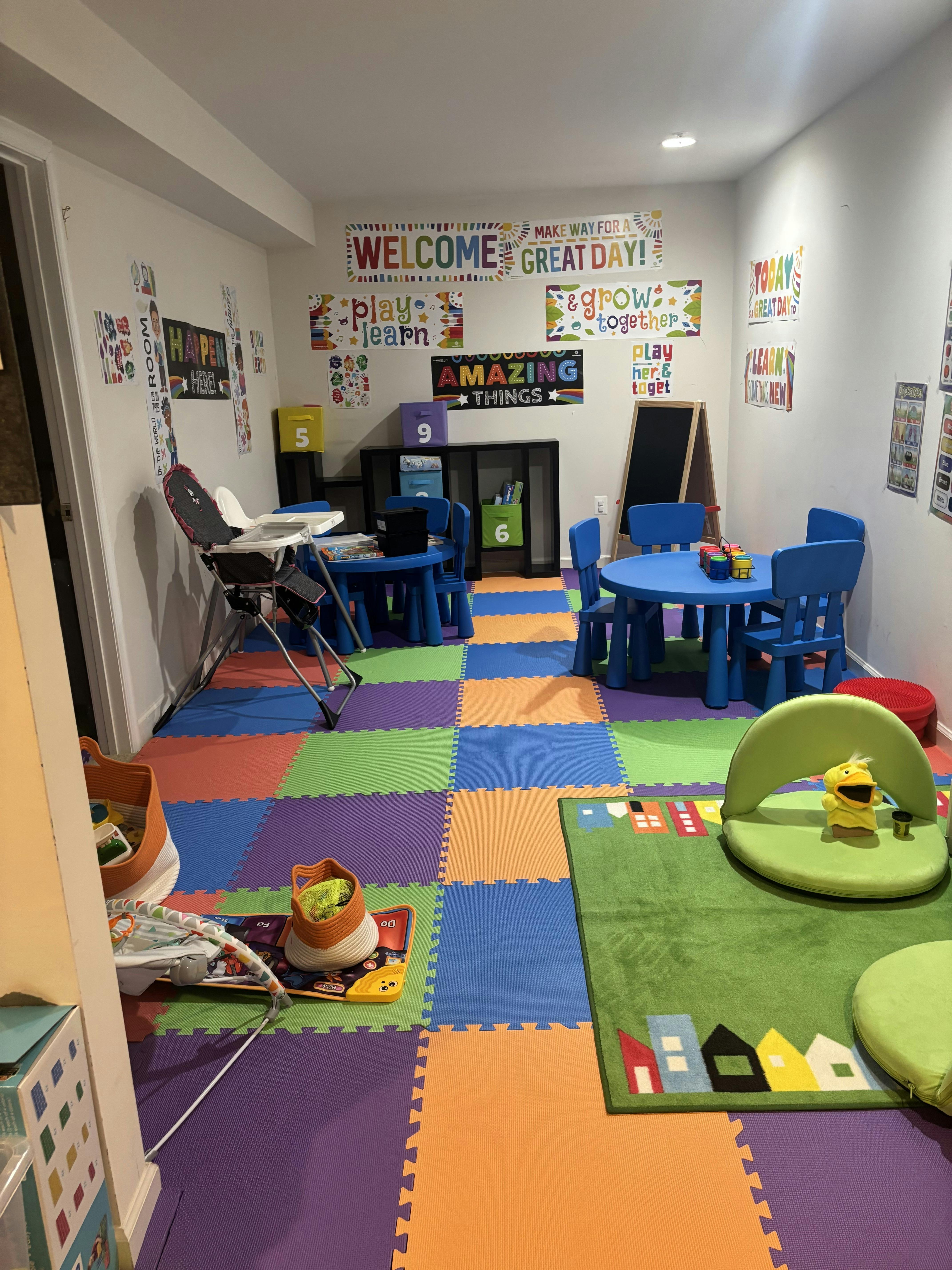 Colorful playroom with small tables, chairs, and learning posters on the walls