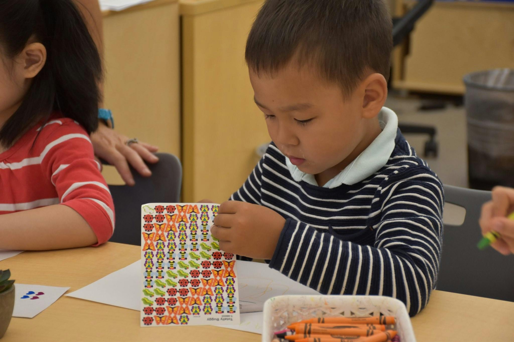 Child peeling stickers from a sheet at a table