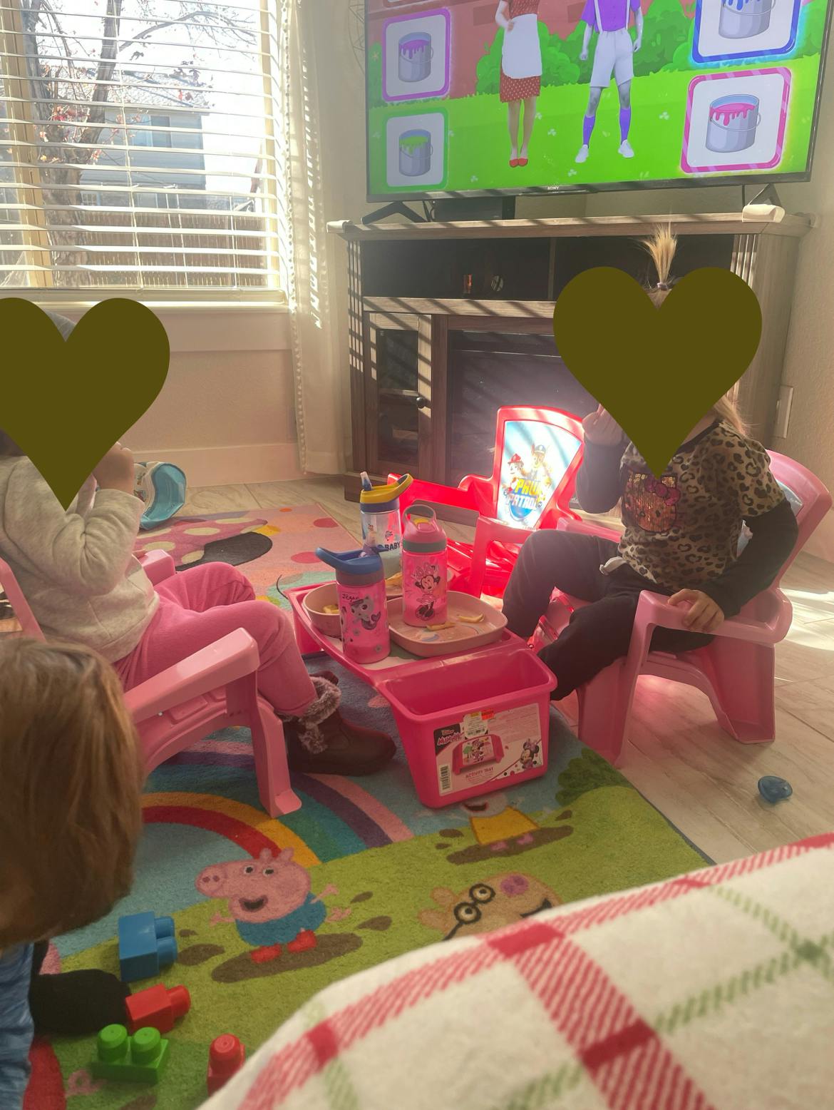 Two children sitting on a rug watching a television