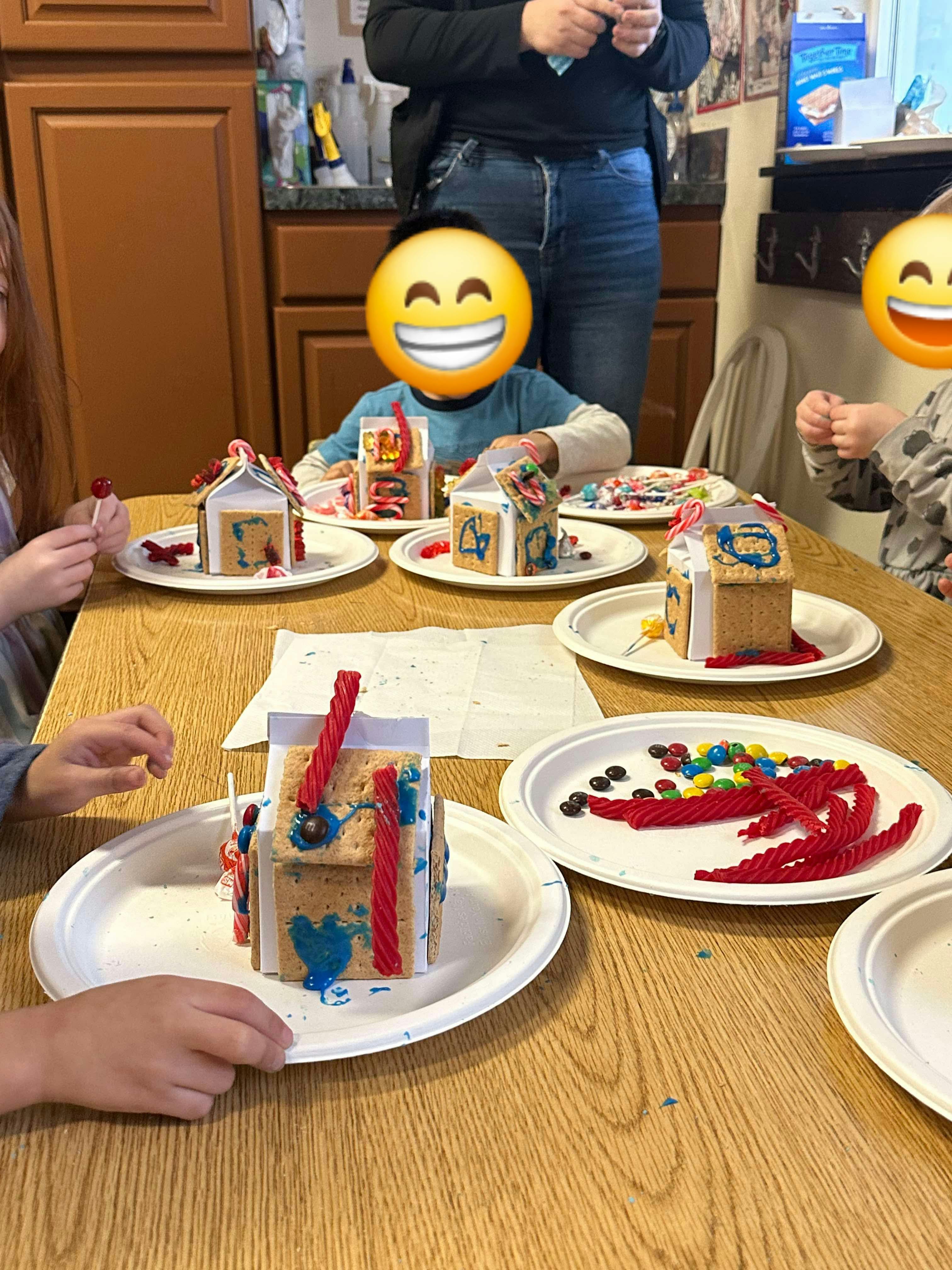 Children decorating small gingerbread houses with candy
