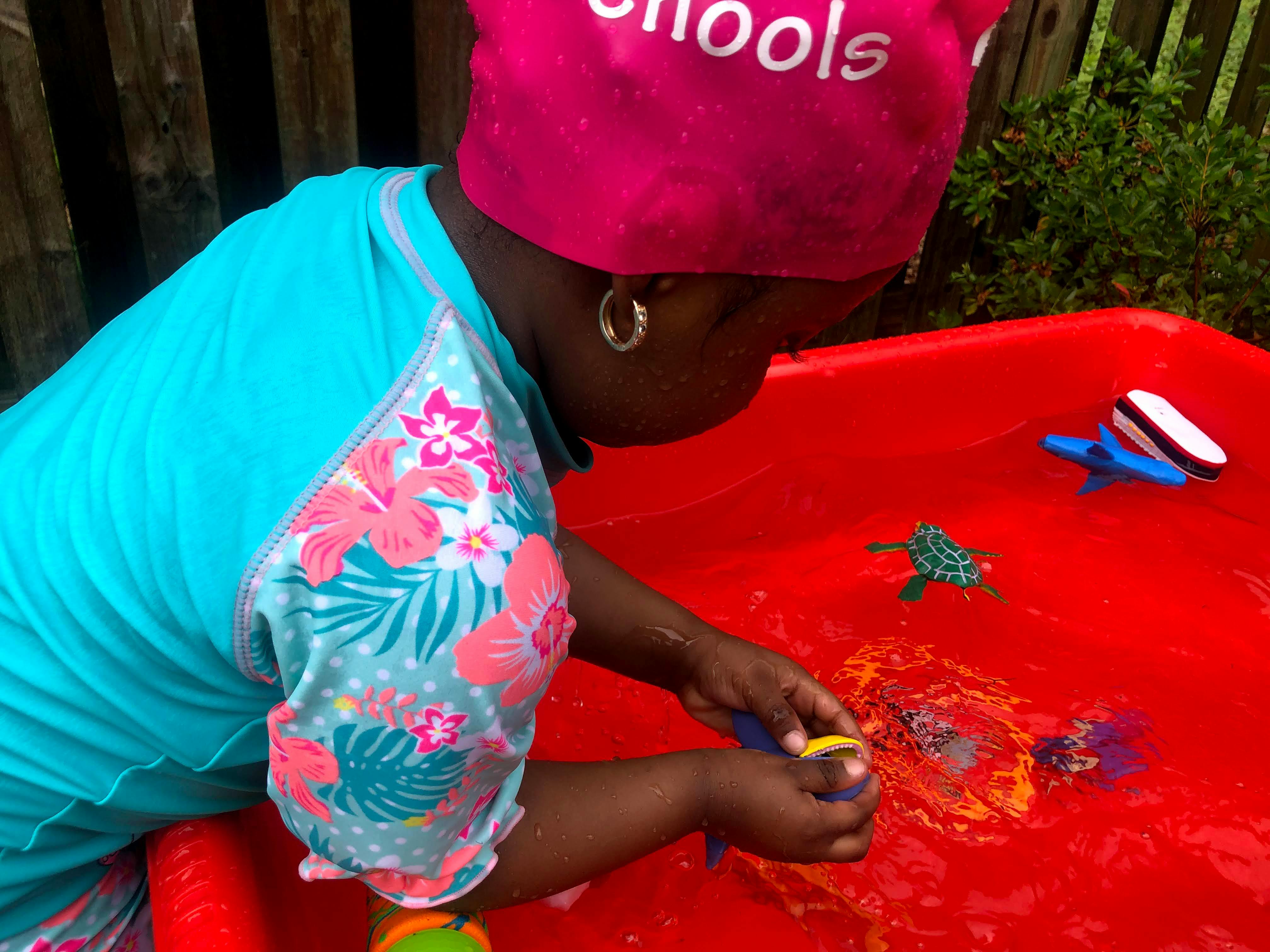 Child playing with toys in a red water table