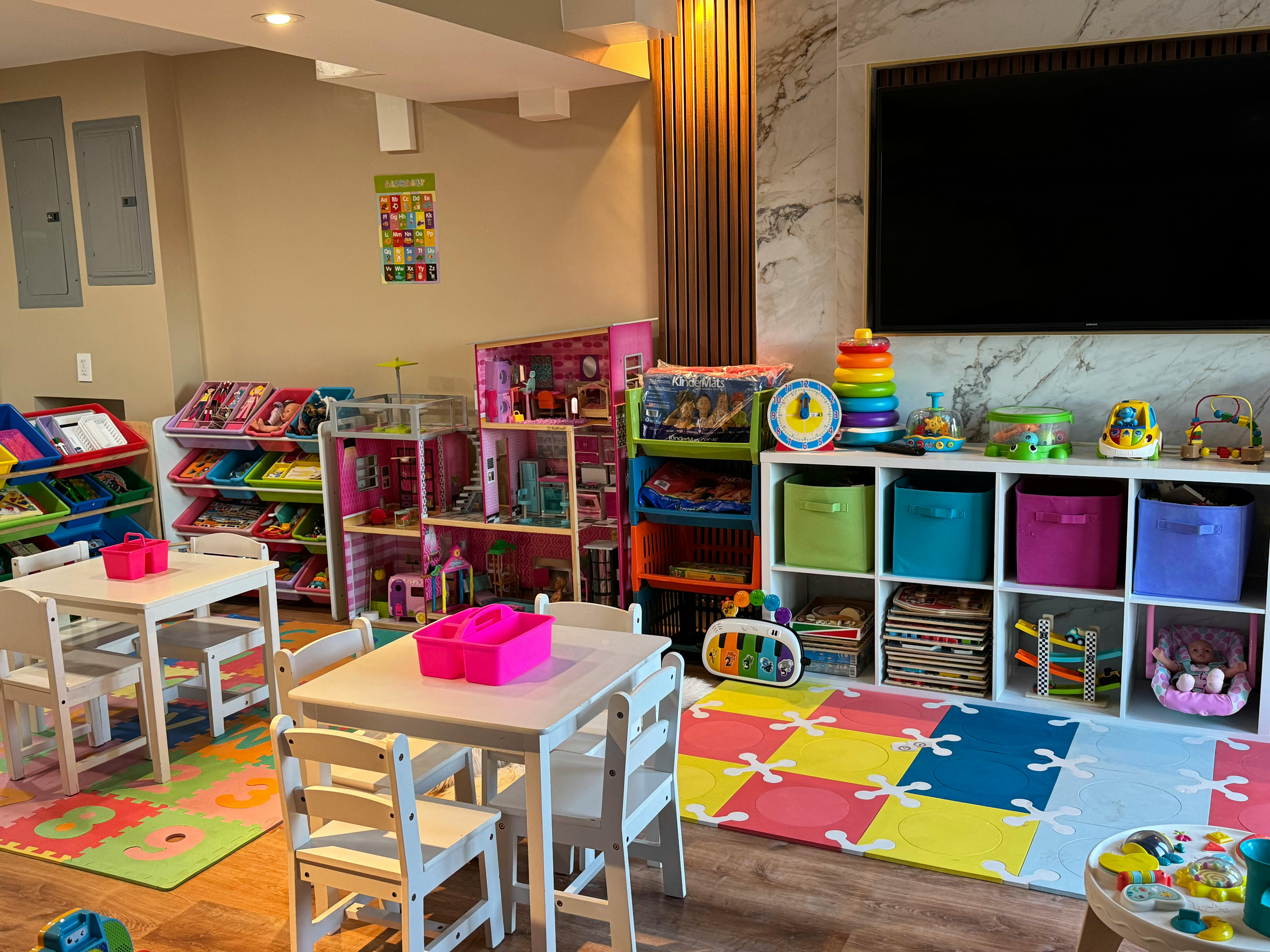 Playroom with small tables and chairs, toy shelves, and a colorful mat