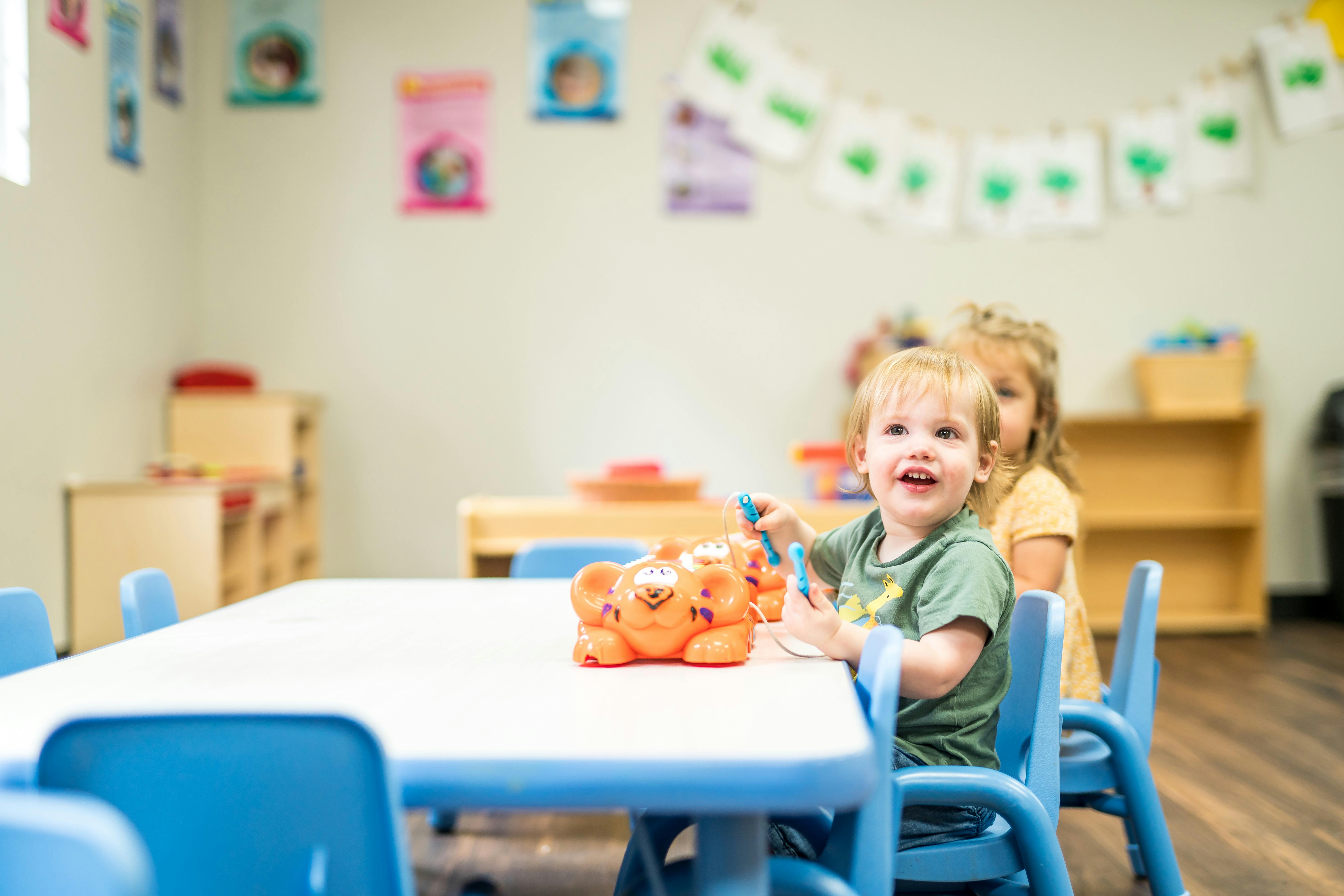 Child playing with a toy at a table in a classroom