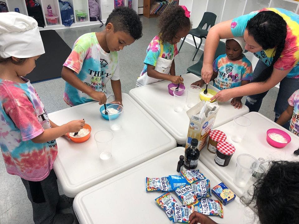 Adult and children mixing ingredients in bowls at tables