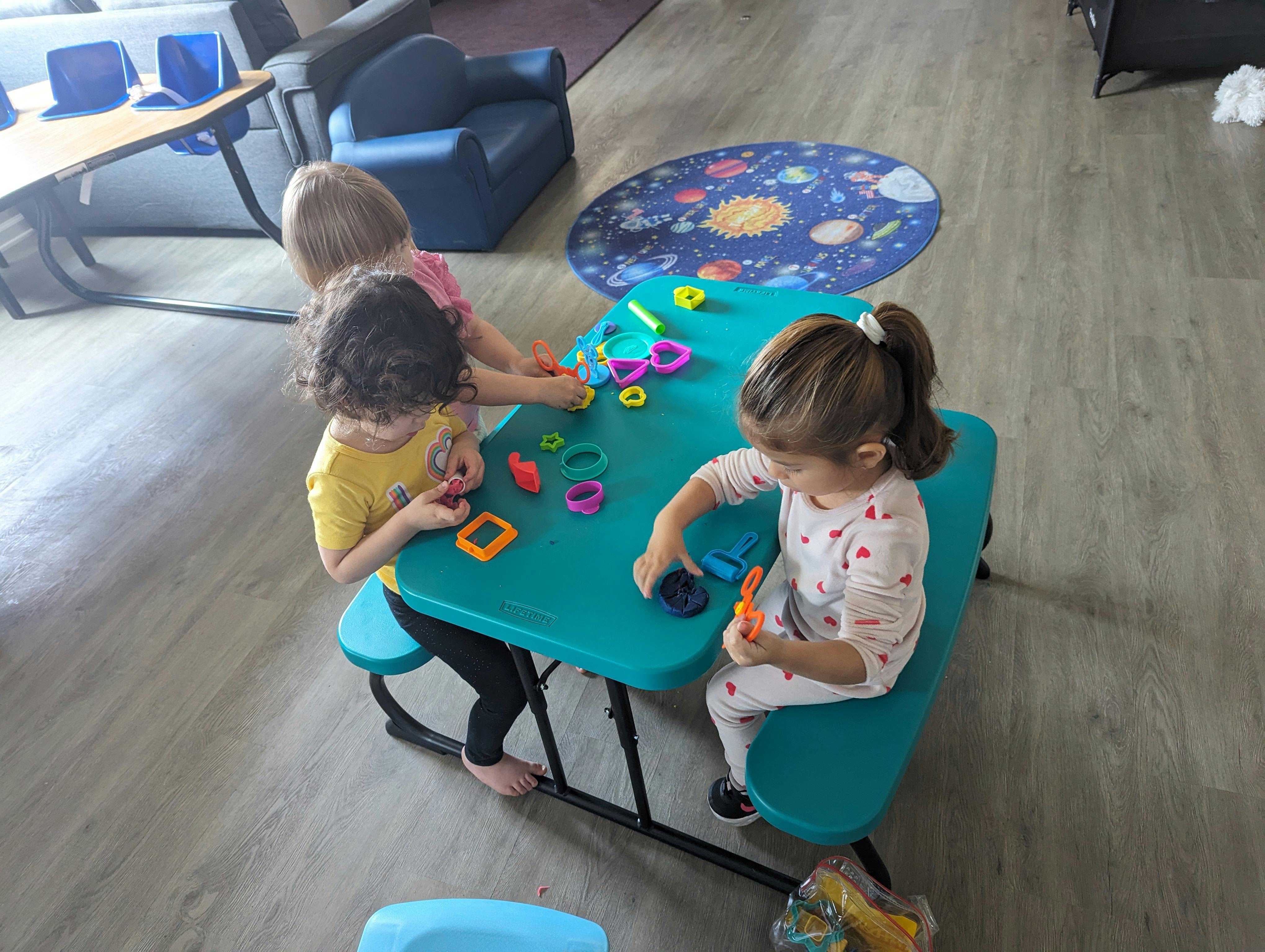 Three children playing with toys at a small table