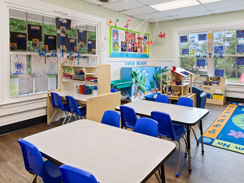 Classroom with tables and chairs, decorated with child art and educational materials