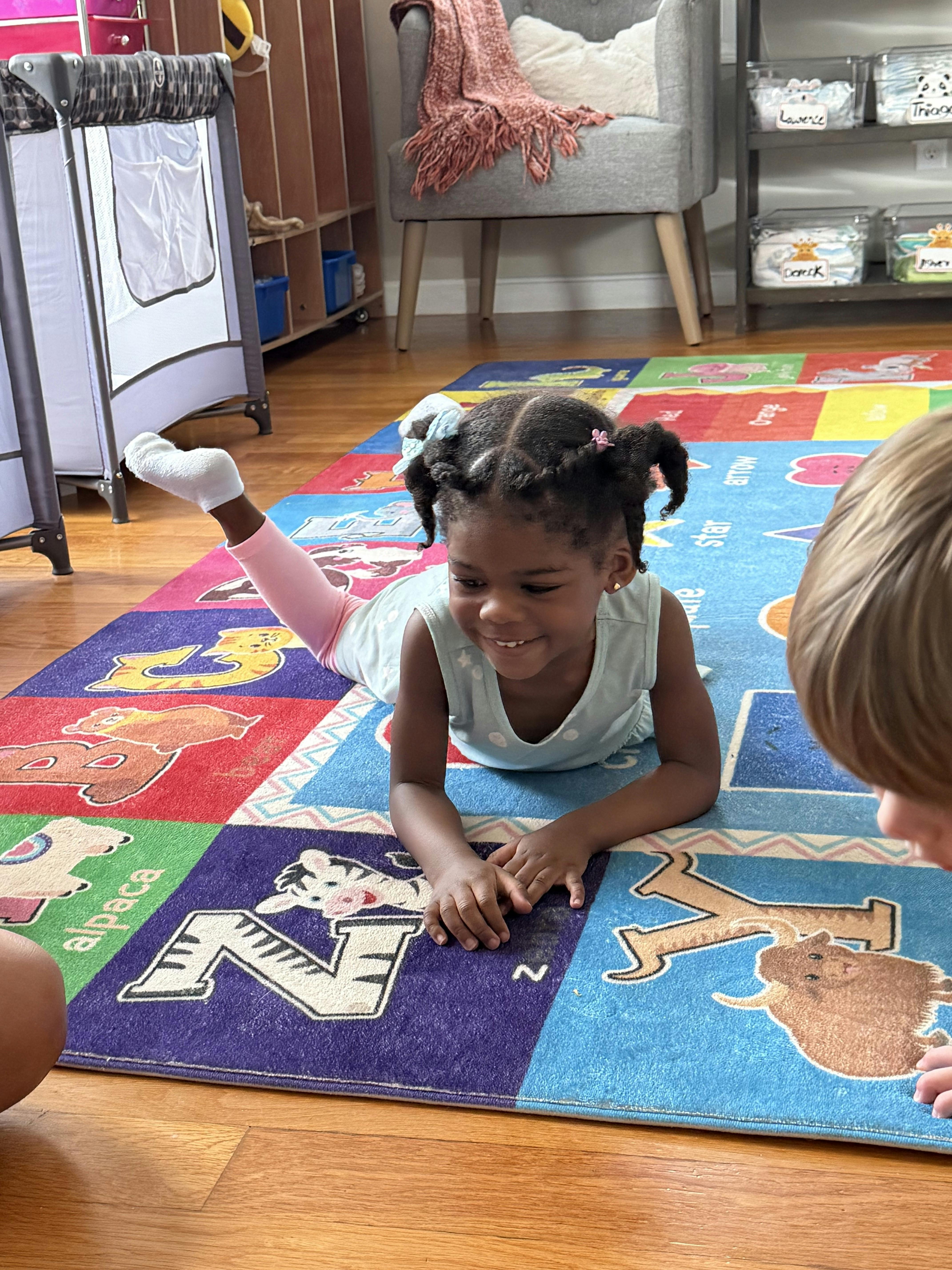 Child lying on an alphabet rug in a classroom