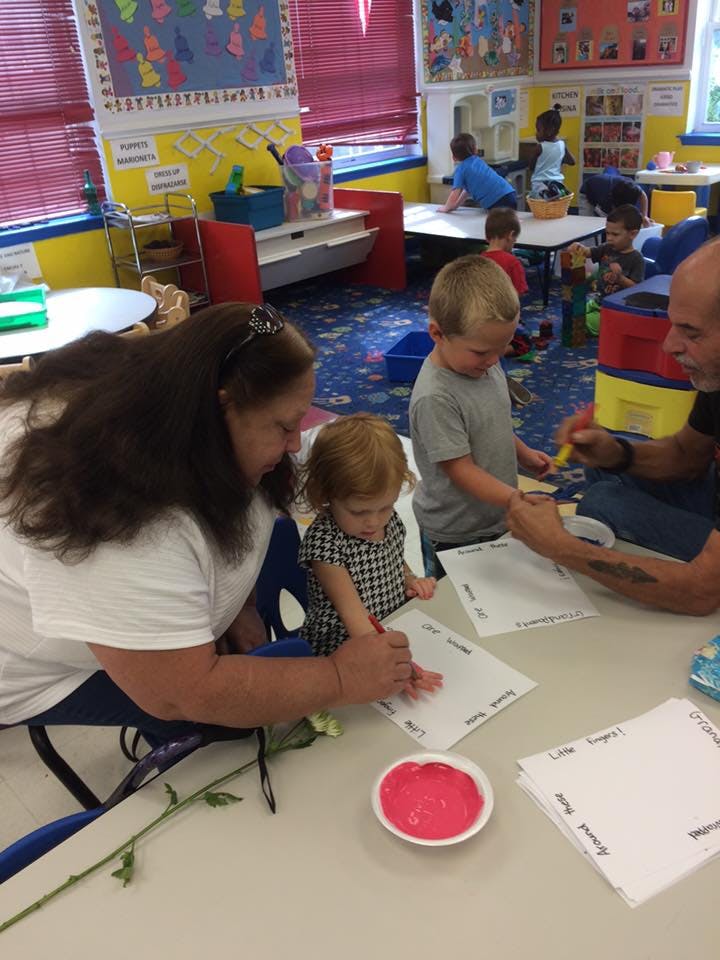 Adults and children doing an art activity with paint in a classroom