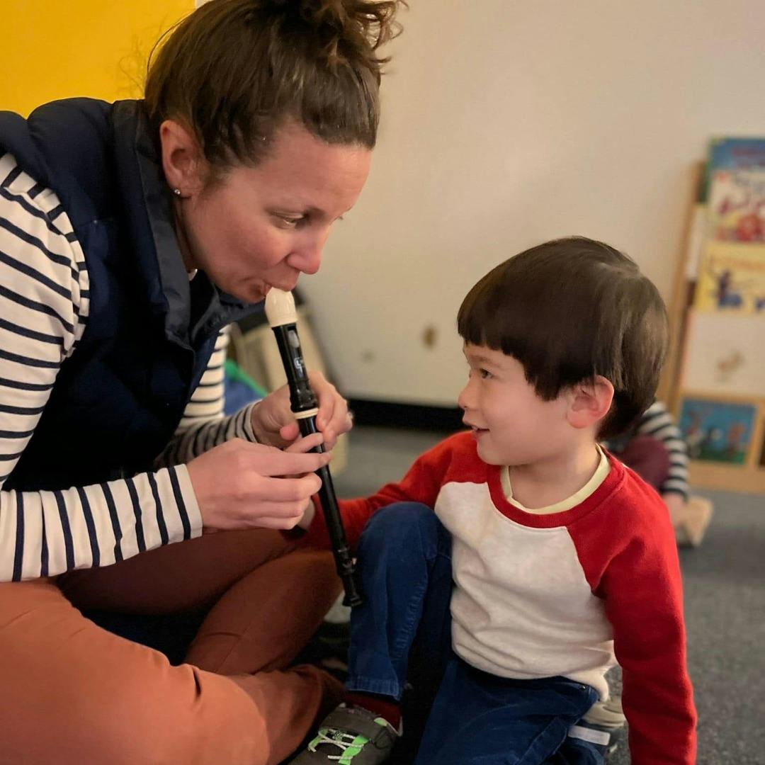 Person playing a recorder for a child