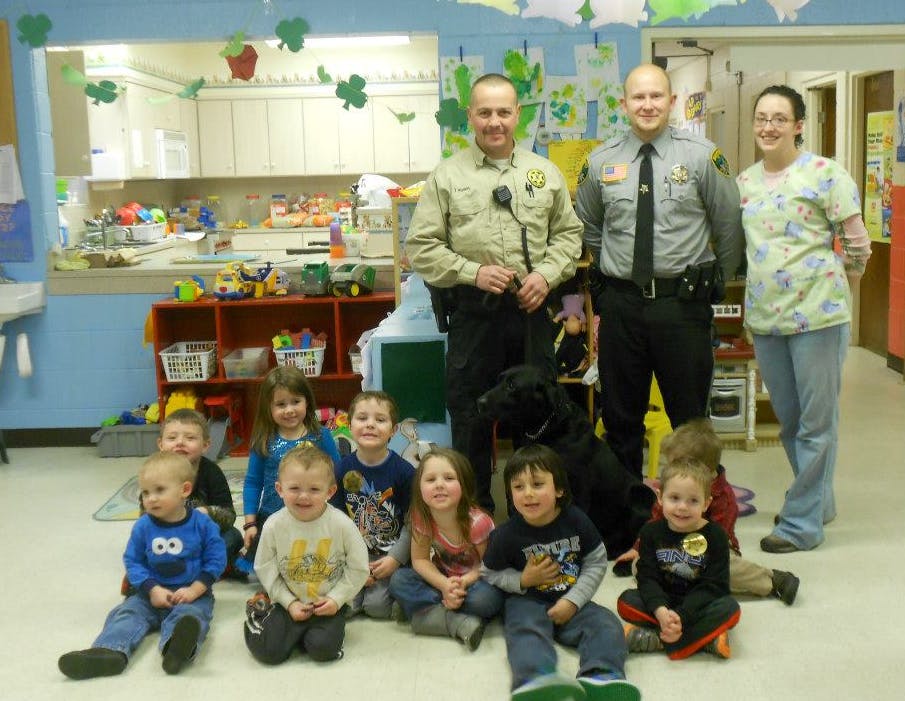 Two people in uniform and one person in scrubs with children and a dog