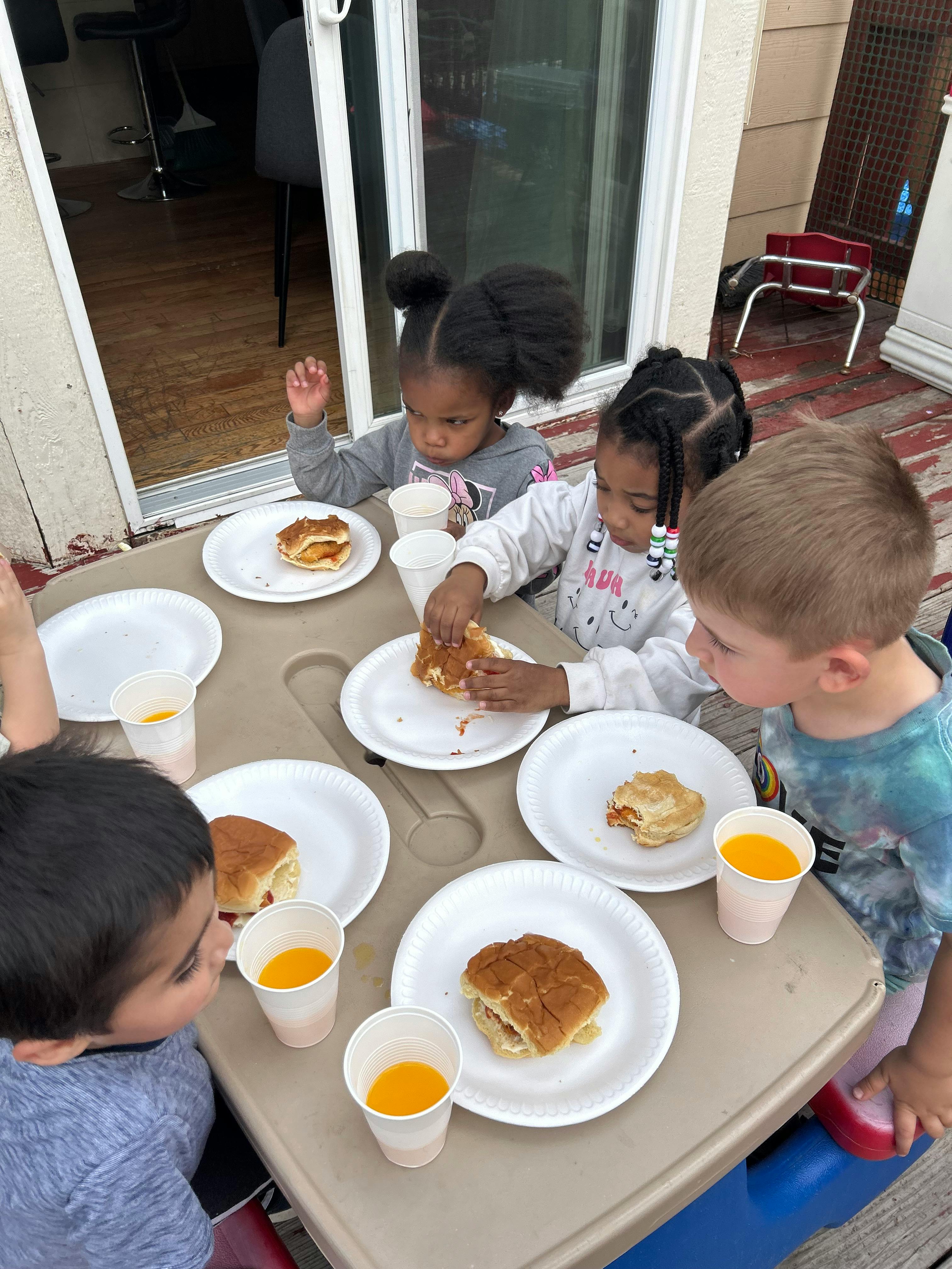 Children eating sandwiches and drinking juice at a table
