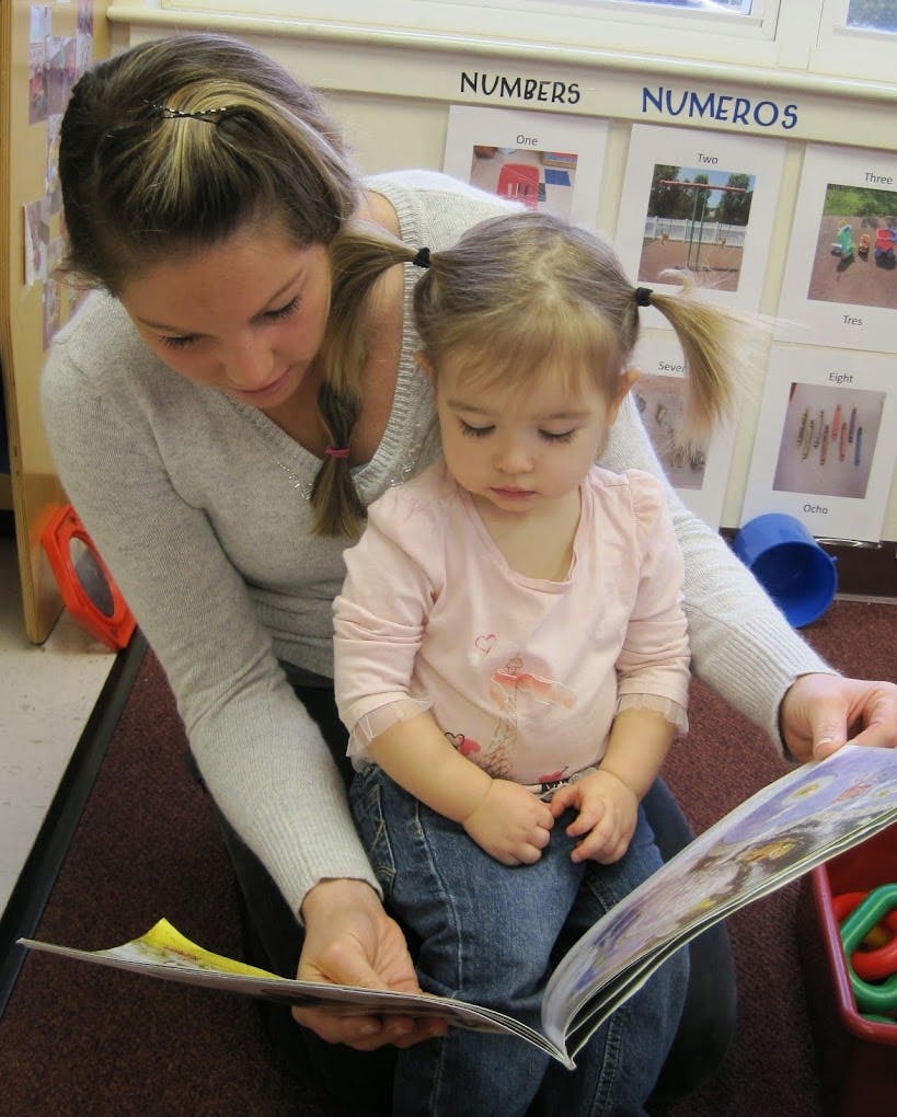 Person and child reading a book together