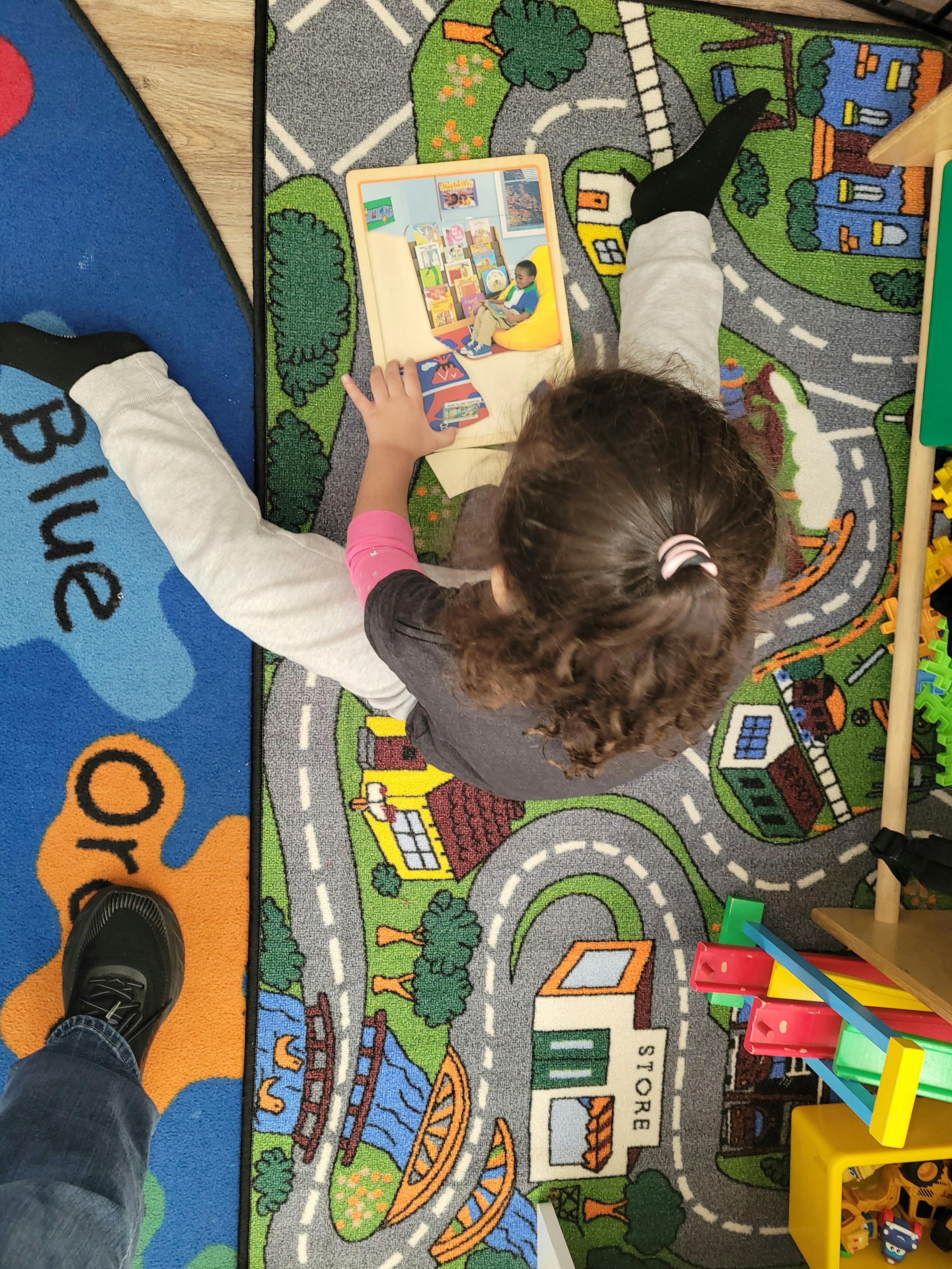 Child sitting on a play rug while working on a jigsaw puzzle
