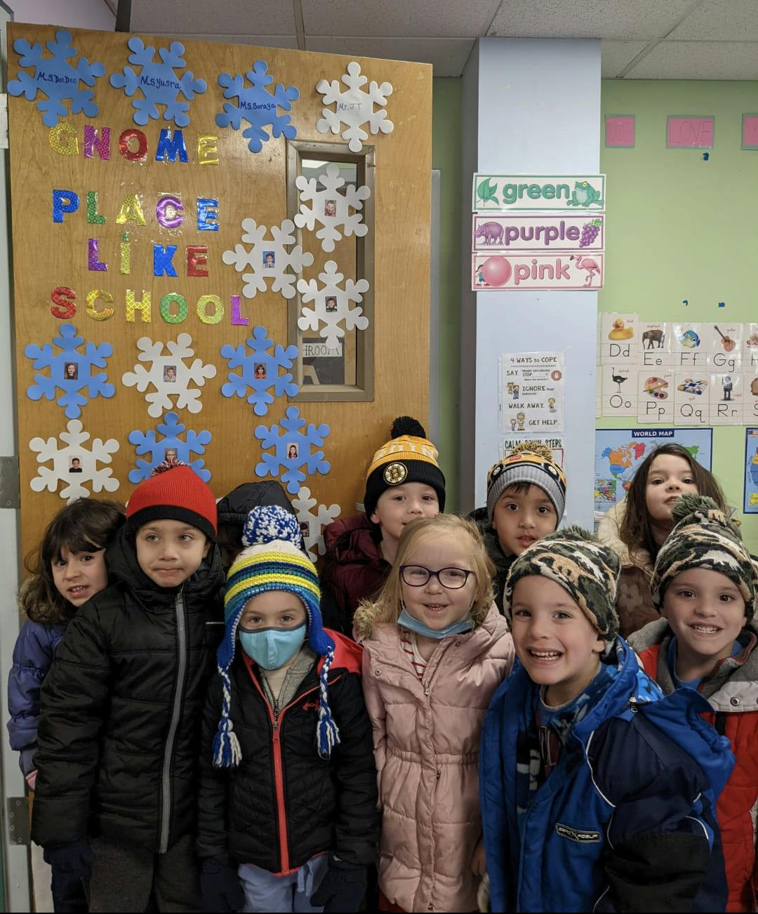 Group of children in winter coats and hats standing in a classroom