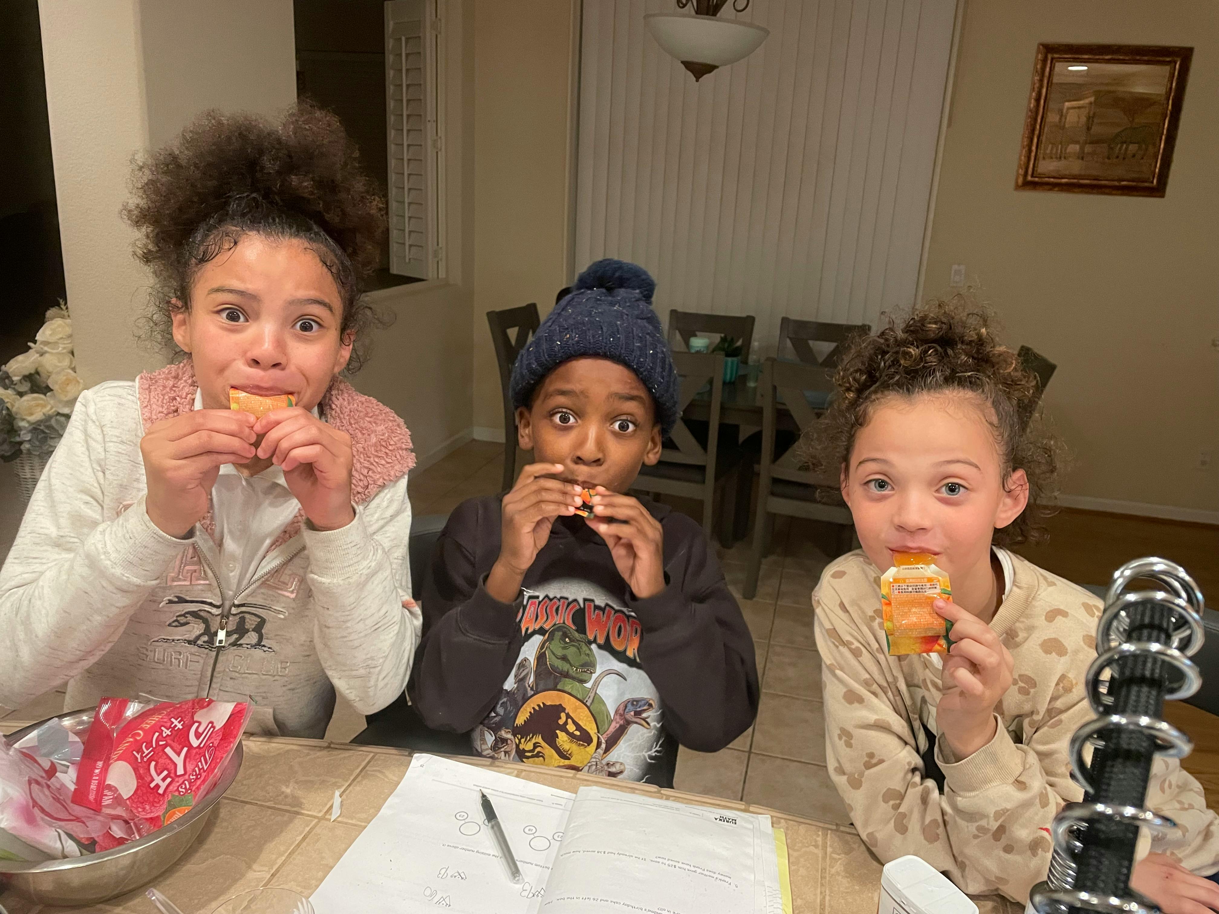 Three children eating snacks at a table