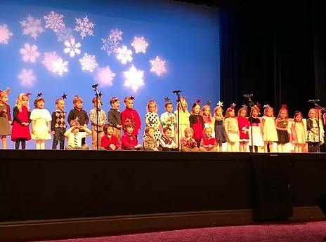 Children on a stage with snowflake projections