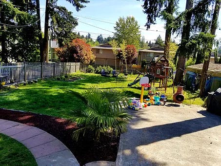 Backyard with green lawn, patio, and children's play equipment