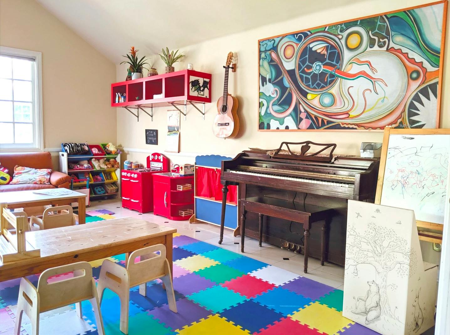 Playroom with colorful floor mats, small tables, a piano, and toys