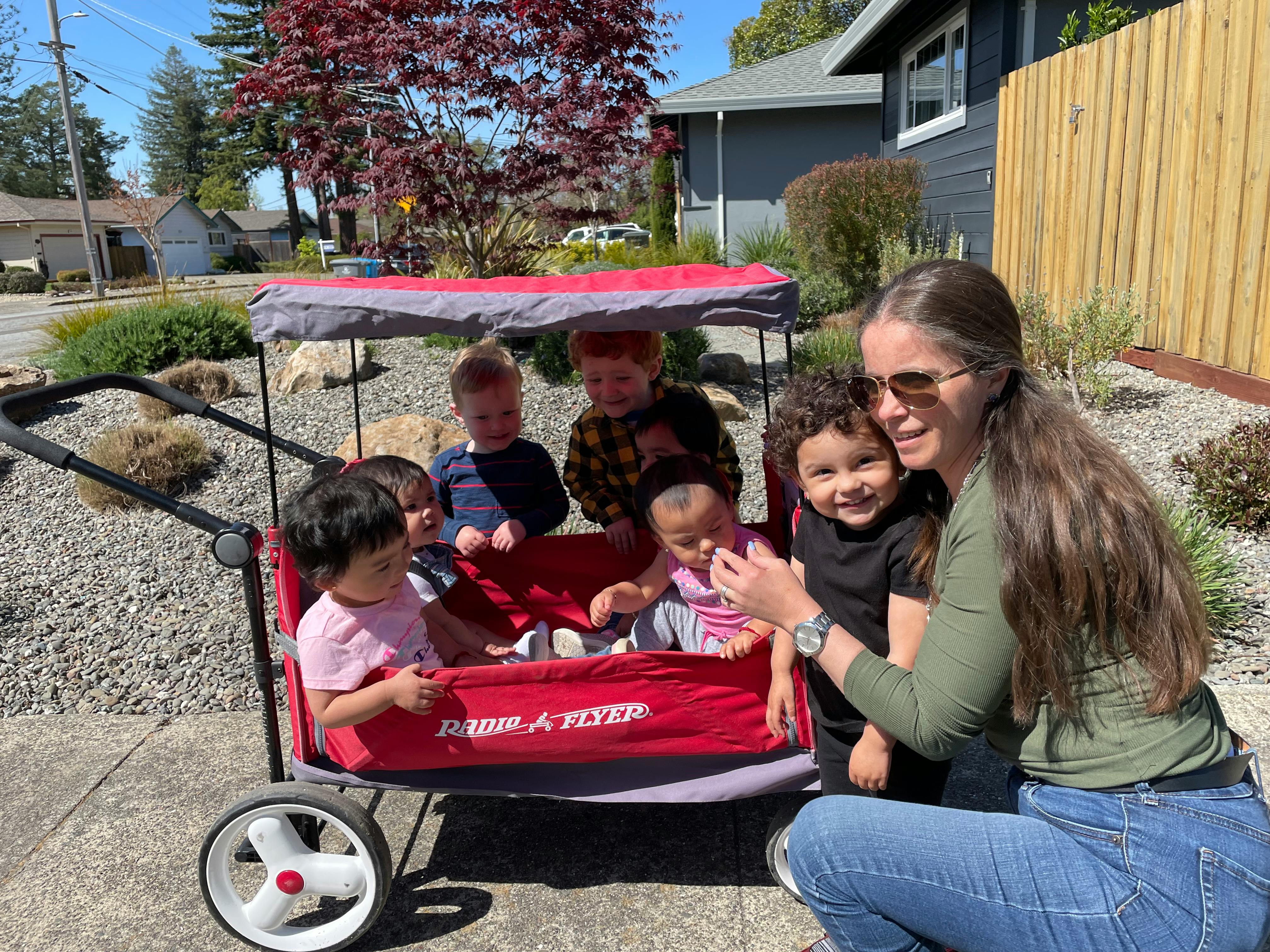 Person kneeling next to a wagon with multiple children
