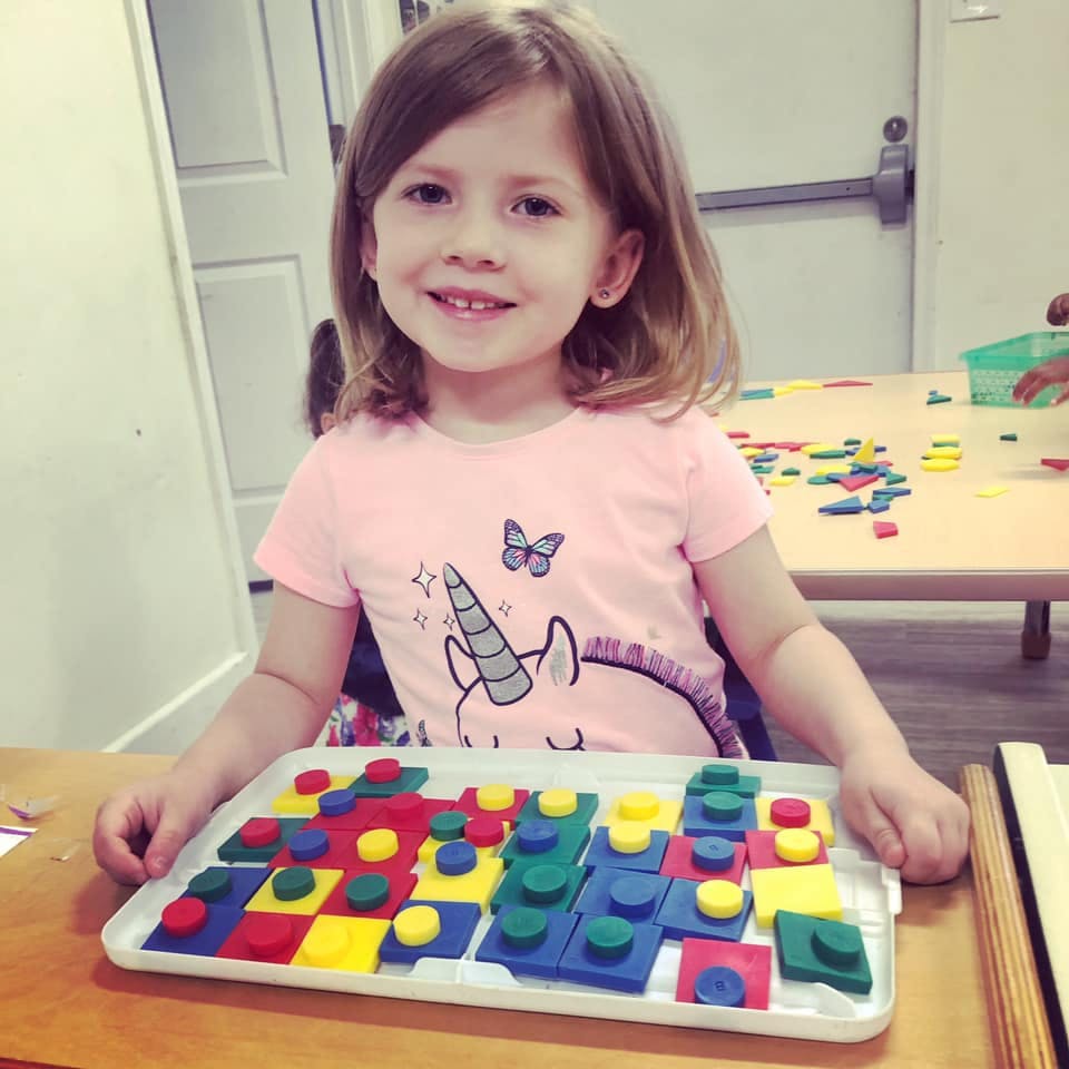 Child playing with colorful blocks on a tray