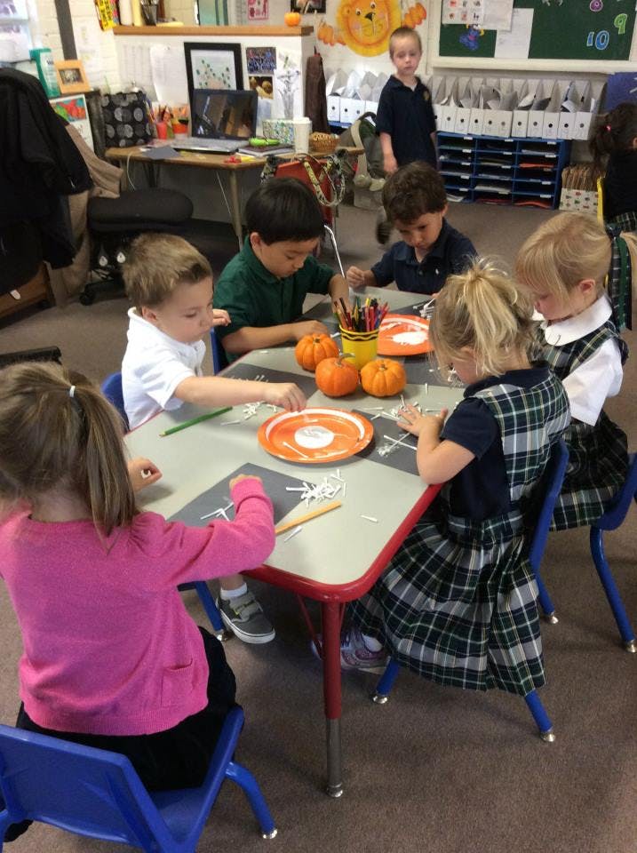 Children at a table doing crafts with small pumpkins