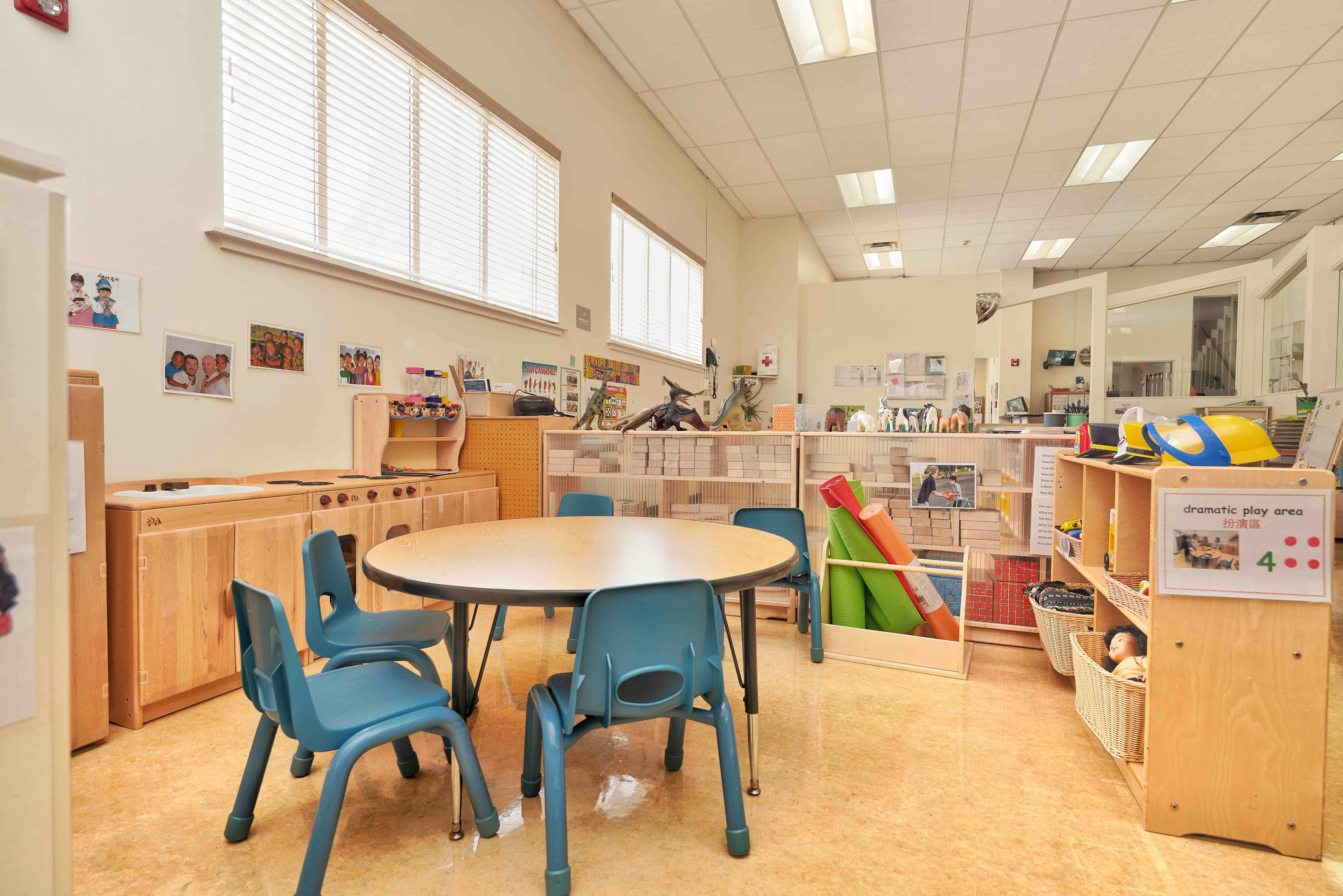 Classroom interior with a round table, small chairs, and a dramatic play area