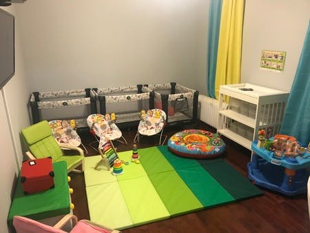 Playroom with multiple cribs, chairs, and play mats