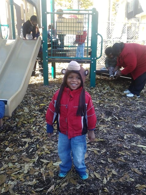 Child in a monkey hat and red jacket on a playground