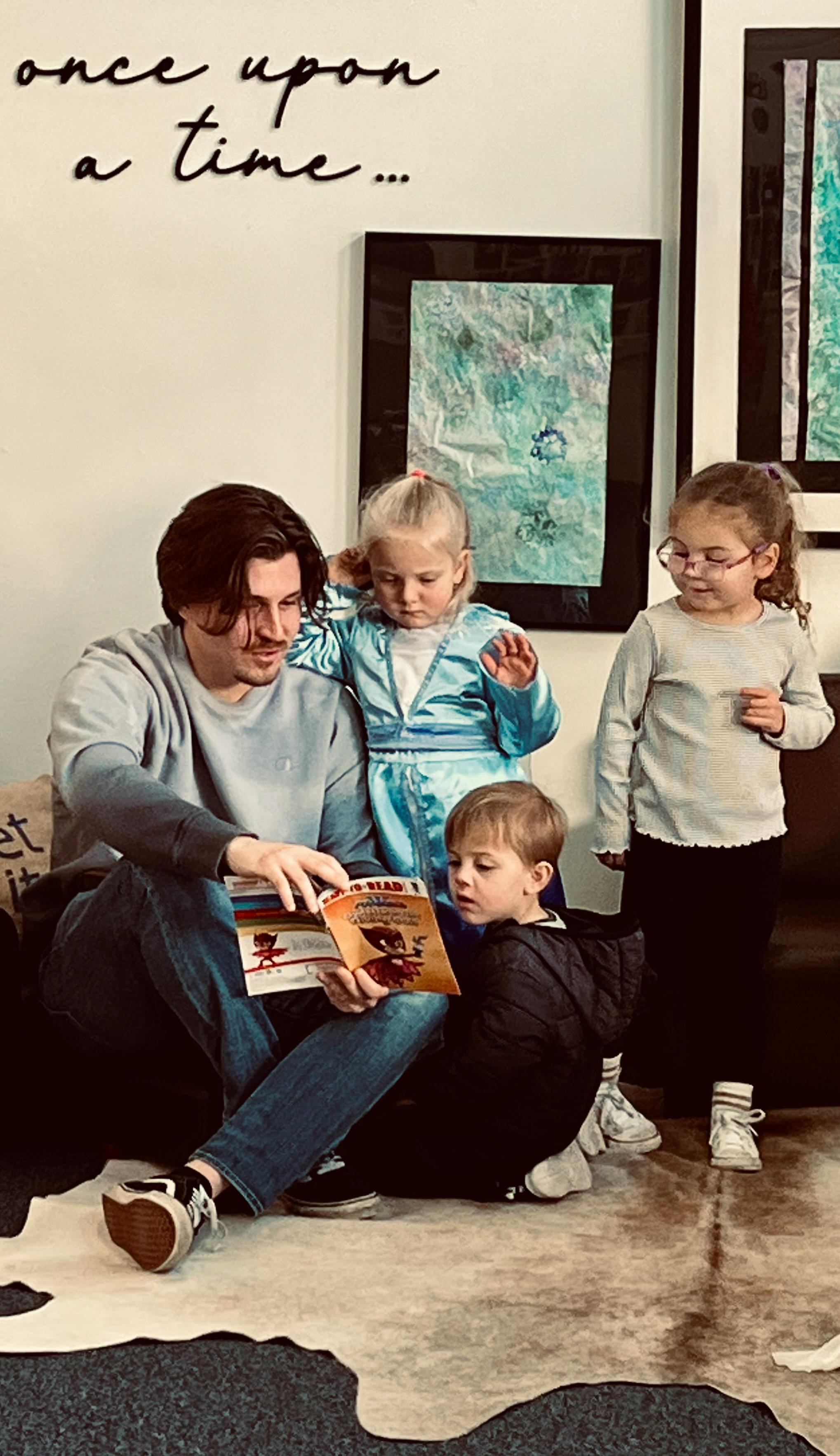 Person reading a book to three children