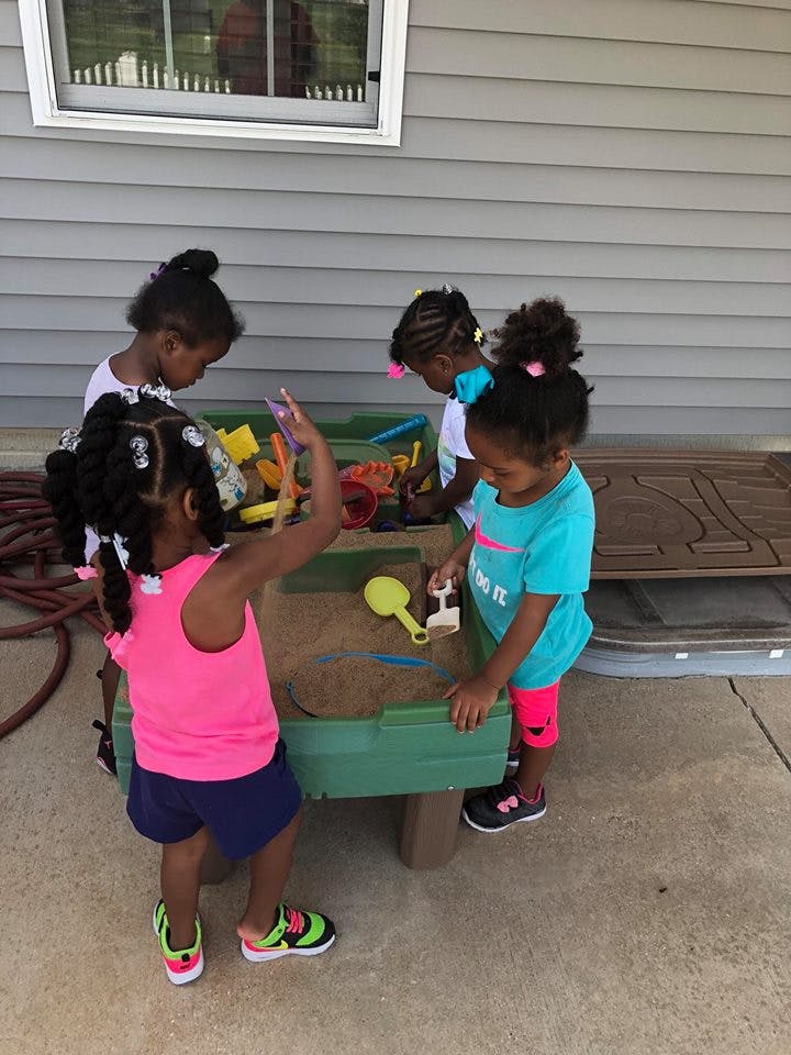 Four children playing at a sand table outdoors