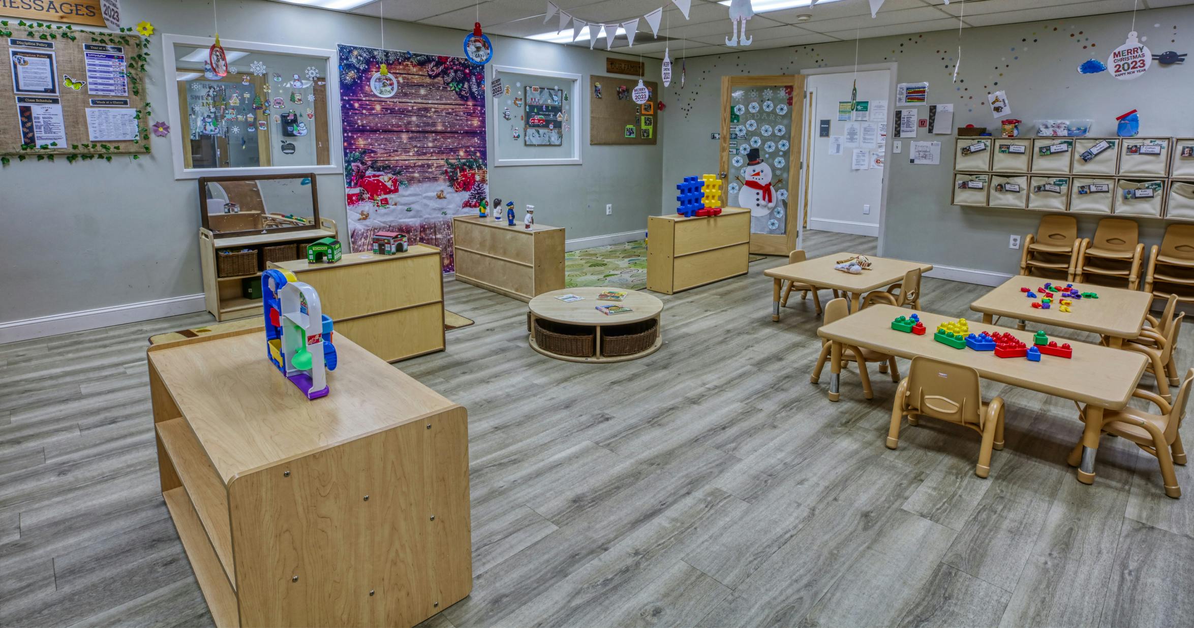 Classroom with small tables, chairs, toy blocks, and holiday decorations