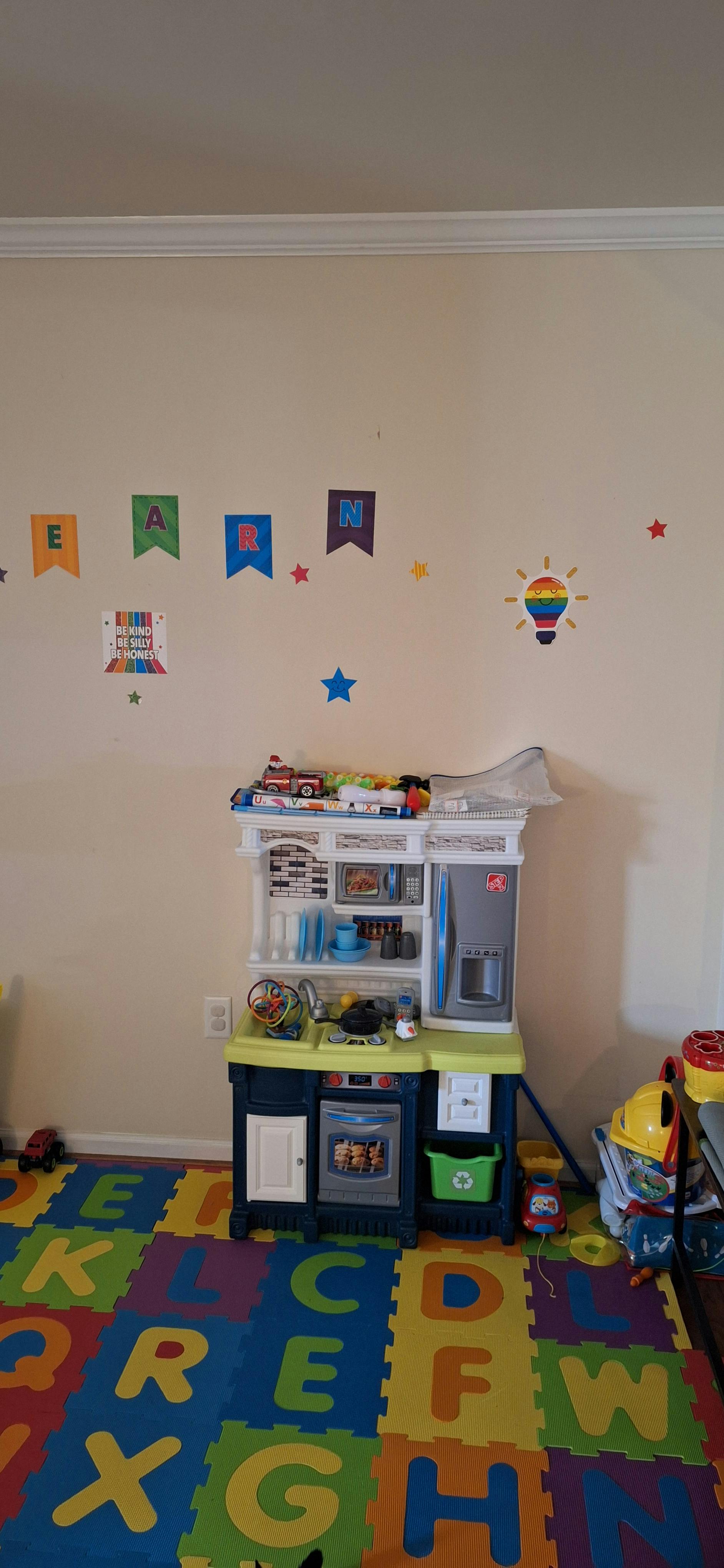 Children's play kitchen with alphabet floor mats and wall decorations