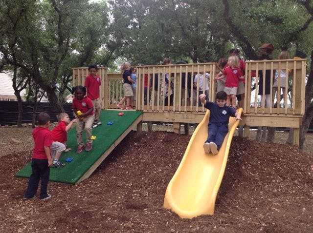 Children playing on a playground with a slide and climbing wall