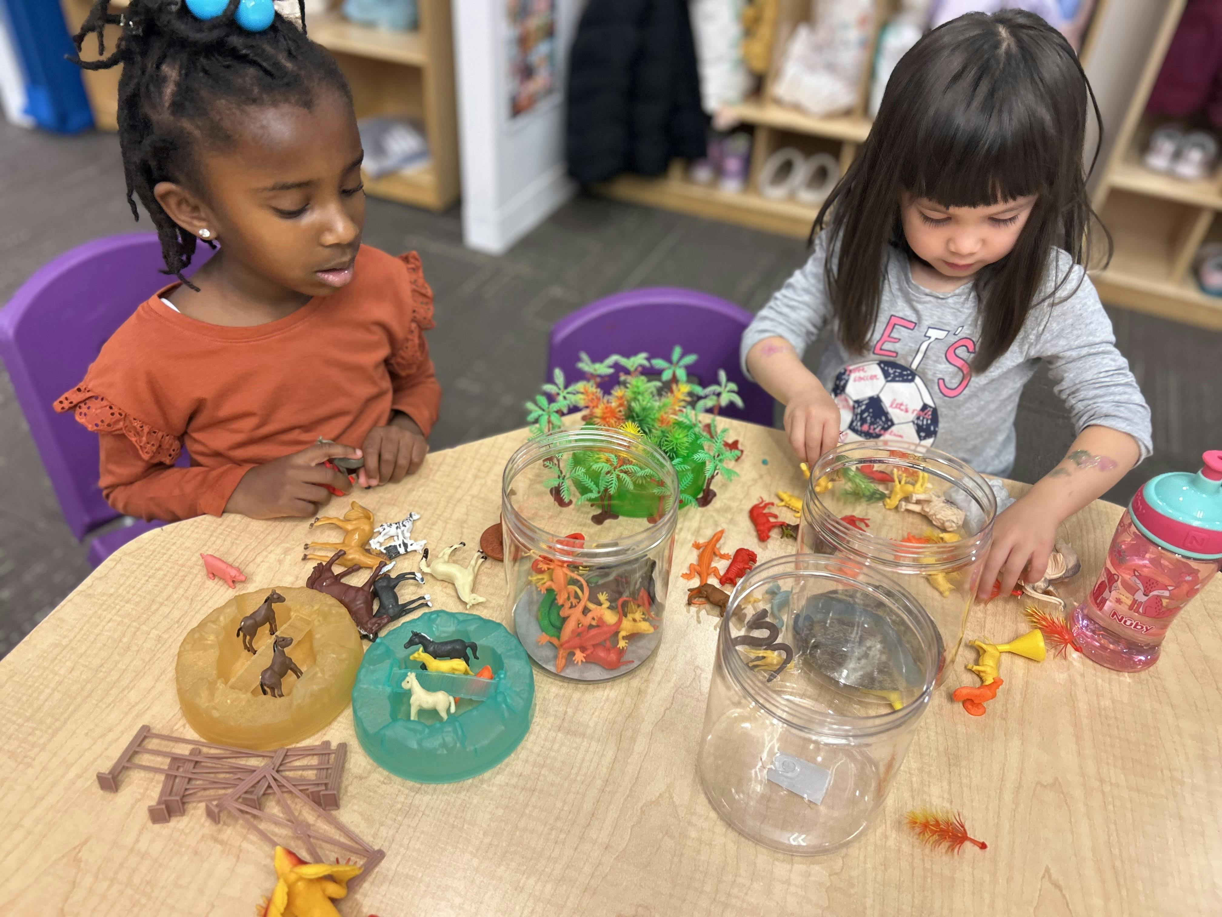 Two children playing with toy animals at a table