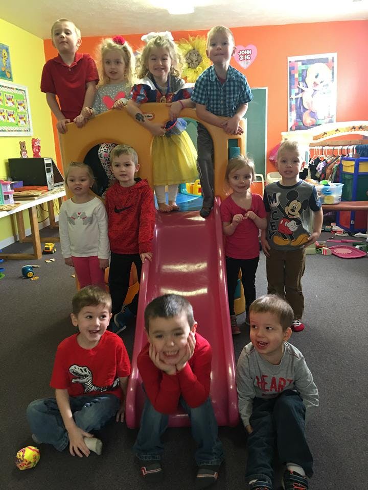 Group of children posing around a small indoor slide