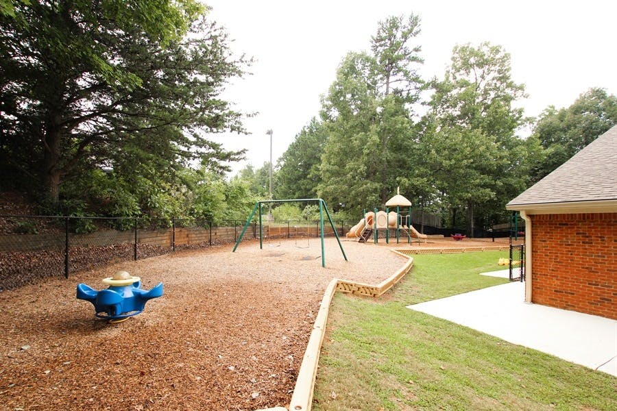 Outdoor playground with swings, slide, and spring rider