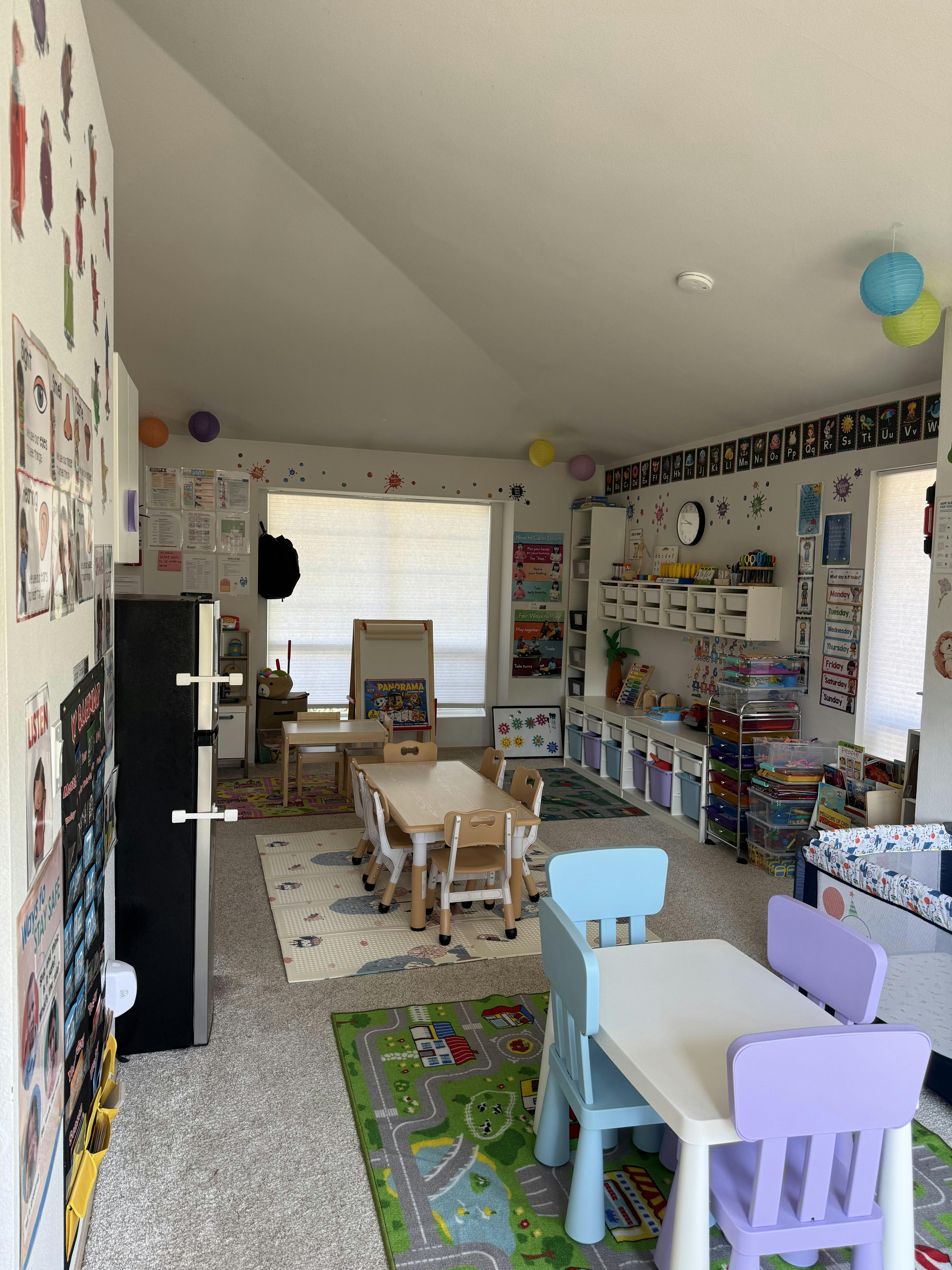 Childcare classroom with small tables and chairs and educational wall charts