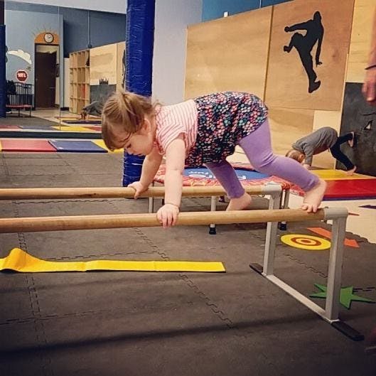 Child climbing over parallel bars in a gym
