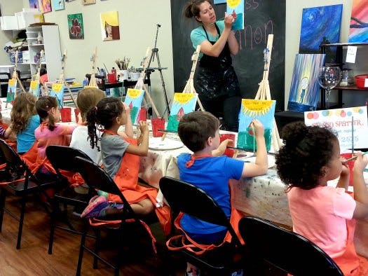 Adult teaching children how to paint in a classroom