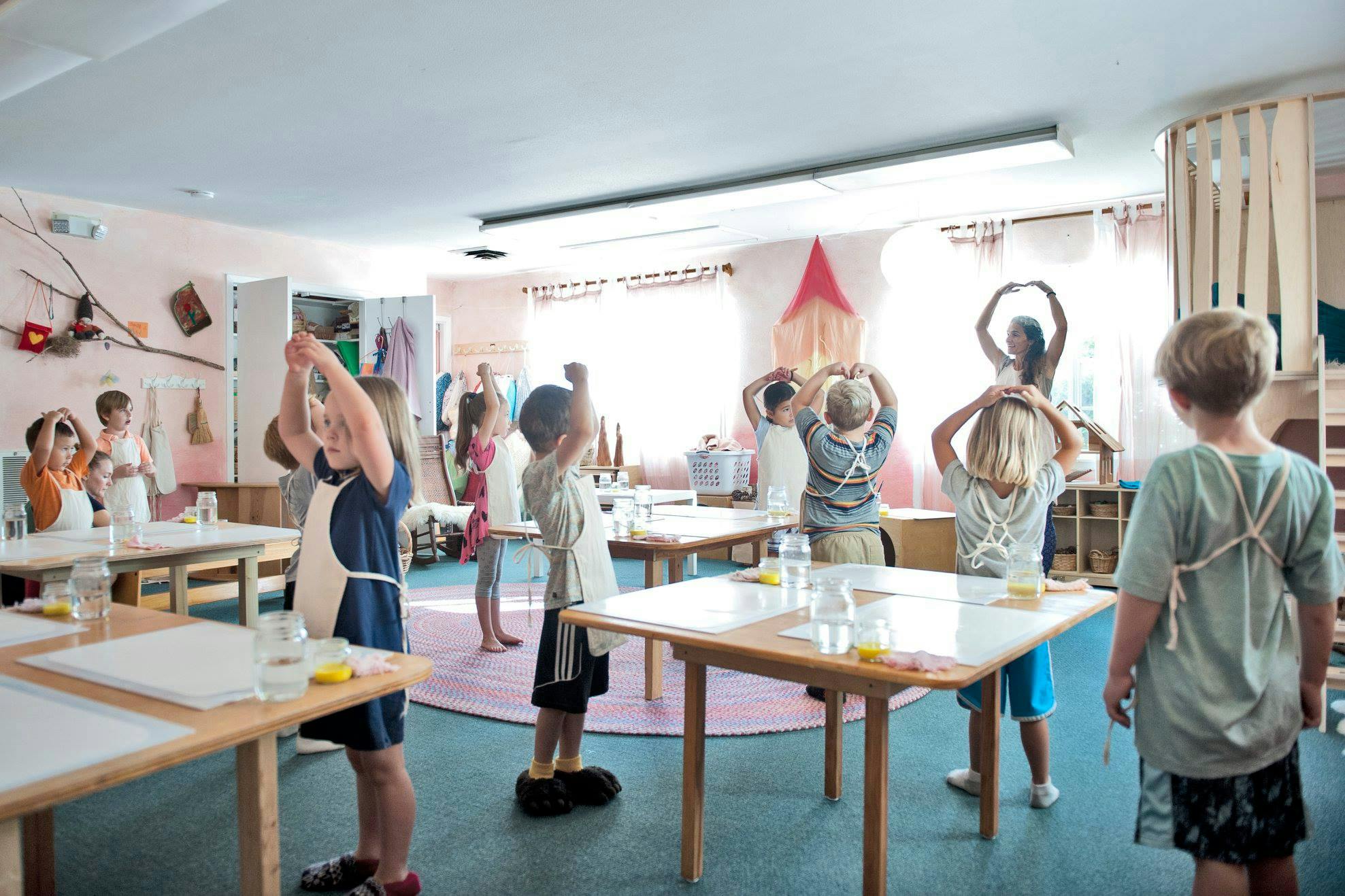 Children in a classroom with arms raised