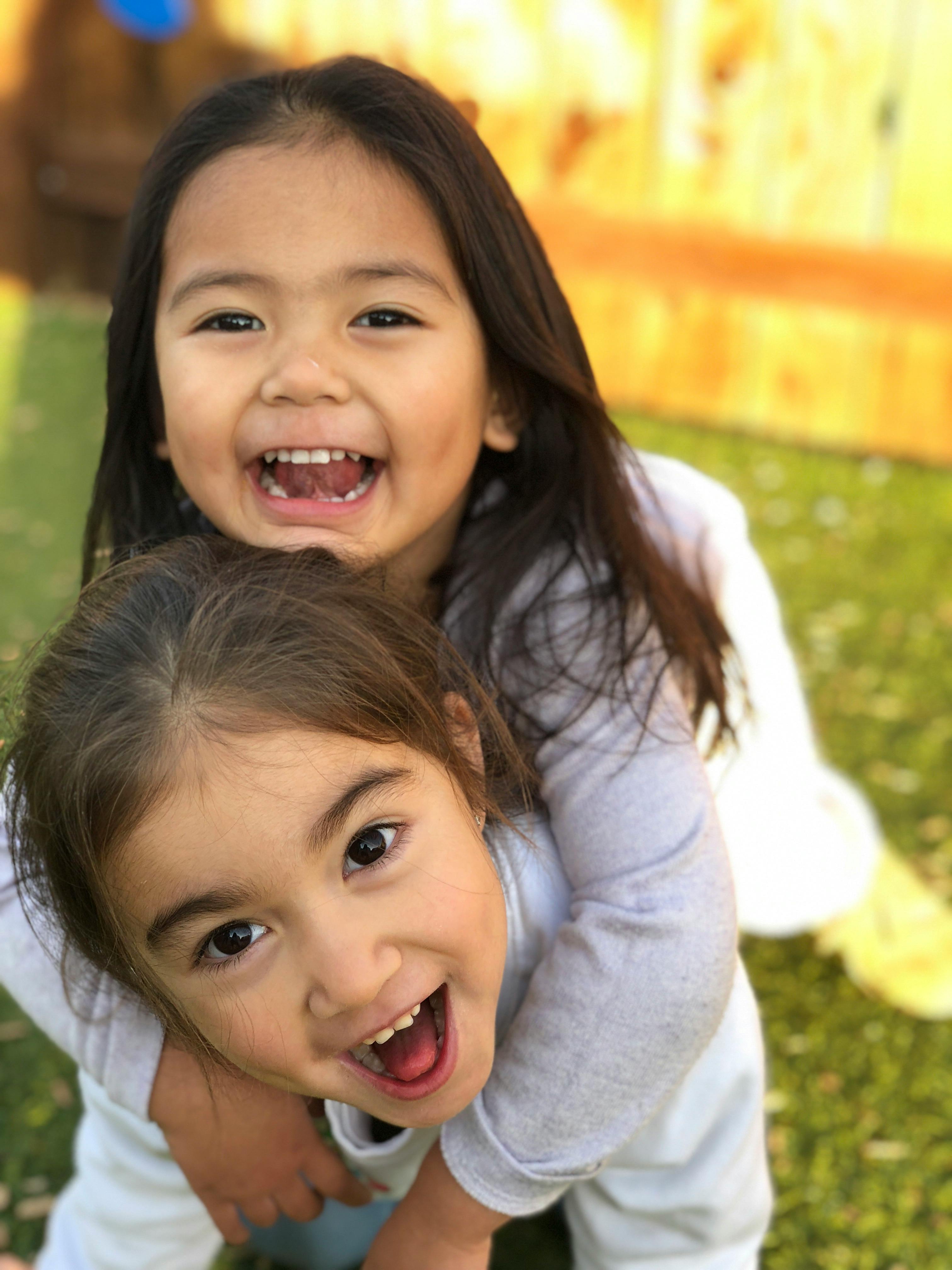 Two children smiling, one piggybacking on the other