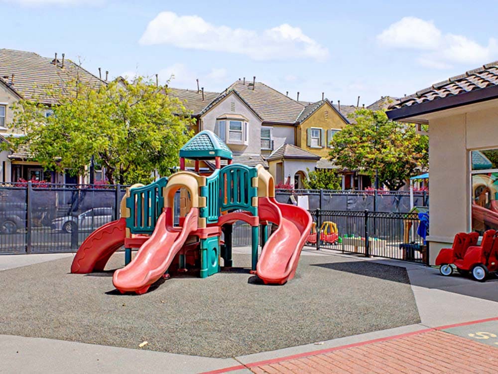A children's playground with a large red and green slide structure