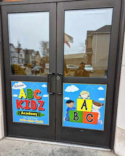 Double doors with "ABC KIDZ Academy" sign and children playing with ABC blocks